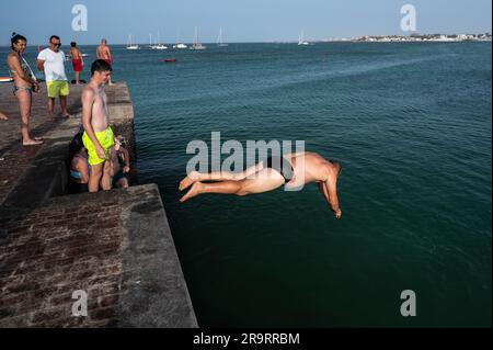 Fuerteventura, Spanien. 28. Juni 2023. Menschen springen im Hafen von Corralejo, nördlich von Fuerteventura auf den Kanarischen Inseln ins Wasser. Die Menschen versuchen, sich zu erfrischen, während sich die Hitzewelle im Sommer fortsetzt. Kredit: Marcos del Mazo/Alamy Live News Stockfoto