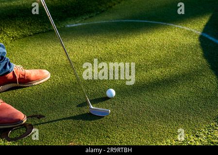 Das Foto eines Mannes in braunen Schuhen spielt Golf auf dem Rasen Stockfoto