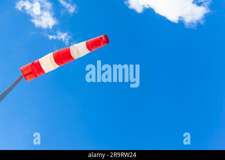 Aufgeblasene Windsocke aus Meteorologie rot-weiß gestreift bis zum blauen Himmel (Kopierbereich) Stockfoto