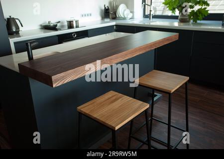 Schäbiger Holztisch mit Stühlen und Vase in der Nähe einer komfortablen Couch an hellen Wänden mit Dekoration in einem modernen Apartment. Hochwertiges Foto Stockfoto