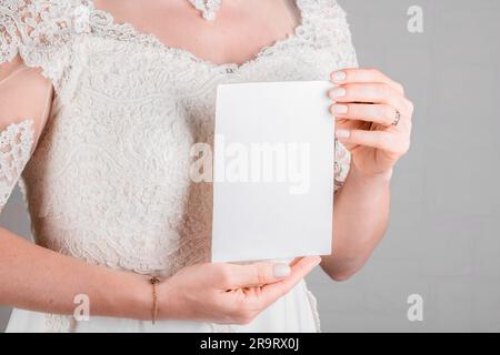 Braut hält Hochzeit Stagionery Einladungskarte Modell 5 x 7 auf weißem Hintergrund. Minimalistisches, leeres Modell, Dankeskarte, Grußkarte, Hochzeitstag Stockfoto