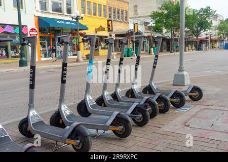 San Antonio, Texas, USA – 8. Mai 2023: Eine Reihe elektrischer Motorroller von Bird, die auf einem Bürgersteig im Zentrum von San Antonio, Texas, geparkt sind. Stockfoto