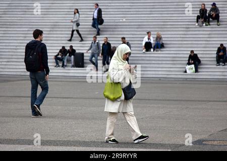 Paris, Frankreich - 25. September 2017: Junge muslimische Frau mit Kopftuch auf dem Stadtplatz vor dem Hintergrund der Pariser ruht auf den Stufen des Stockfoto