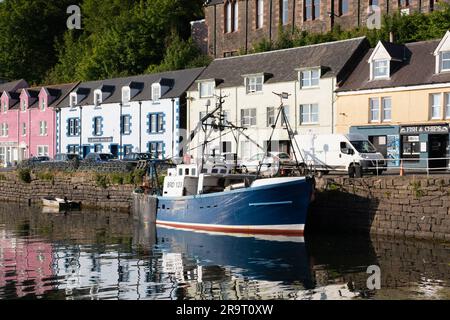 Ein Fischerschiff (Dunan Star II), das am Kai in Portree Harbour, Isle of Skye, vor den bunten Gebäuden in der Quay Street festgemacht ist. Stockfoto