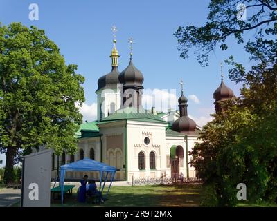 Schwarze Kuppeln der weißen Kirche mit Kreuzen am blauen Himmel. Heiliges Dreifaltigkeitskloster Ioninsky. KIEW UKRAINE 06 06 23 Stockfoto