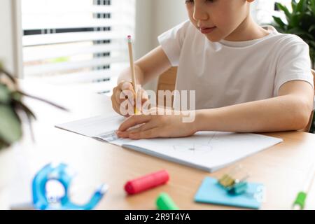 Ein süßer Junge zeichnet mit Lineal und Bleistift. Hausunterricht. Geometrie und Zeichnung. Stockfoto