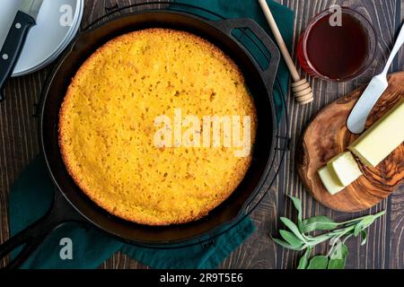 Buttermilch-Cornbread, gebacken in einer gusseisernen Pfanne von oben: Frisch zubereitetes südliches Maisbrot in einer Pfanne mit Butter und Honig an der Seite Stockfoto