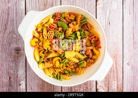 Dreifarbige Pasta, die in einem großen Sieb abgelassen wird: Übersichtsansicht verschiedener dreifarbiger Pasta in einem Kunststoffsieb Stockfoto