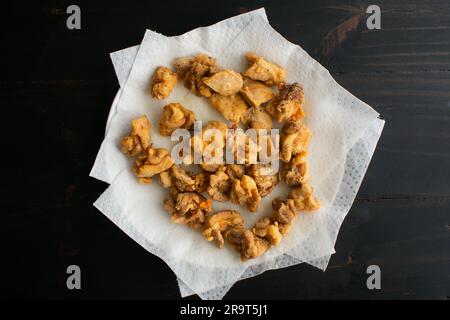Gebratene Hähnchenteile auf Papiertüchern: Frittierte, mundgerechte Hähnchen-Nuggets an den Oberschenkeln auf einem mit Papierhandtüchern bedeckten Teller Stockfoto