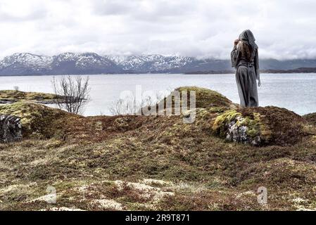 Eine nordische heidnische Frau, die dem Meer ein Opfer bringt. Stockfoto