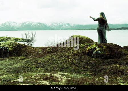 Eine nordische heidnische Frau, die dem Meer ein Opfer bringt. Stockfoto