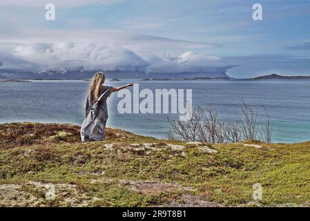 Eine nordische heidnische Frau, die dem Meer ein Opfer bringt. Stockfoto