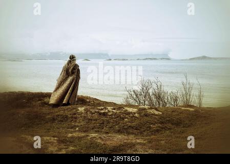 Eine nordische heidnische Frau, die dem Meer ein Opfer bringt. Stockfoto