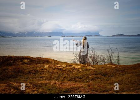 Eine nordische heidnische Frau, die dem Meer ein Opfer bringt. Stockfoto