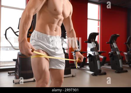 Sportler, der im Fitnessstudio mit Klebeband den Oberschenkel misst, Nahaufnahme Stockfoto