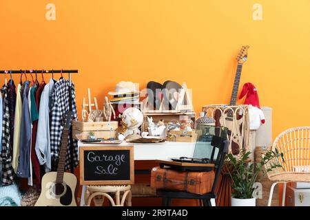 Schild Garage Sale steht an der Tafel in der Nähe von vielen verschiedenen Sachen Stockfoto