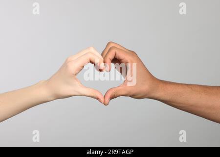 Internationale Beziehungen. Menschen, die Herz machen, mit Händen auf hellgrauem Hintergrund, Nahaufnahme Stockfoto