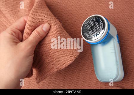 Frau, die einen Pullover mit Fusseln und Textilrasierer hält, Draufsicht Stockfoto