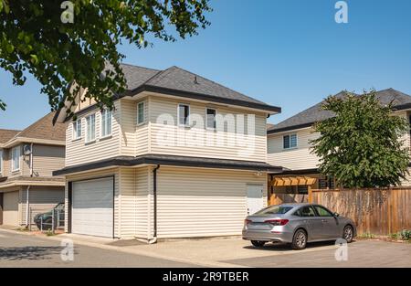 Außenansicht des kleinen neuen Custom Home in Nordamerika. Zweistöckiges Haus mit kleiner Eingangsterrasse und Garage. Wohnhäuser, Unterbereichsentwicklung, Stockfoto