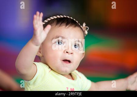 Porträt eines glücklichen, wunderschönen 10 Monate alten Mädchens mit bunten Hintergründen. Frühstimulierungs-Konzept für Kleinkinder. Stockfoto