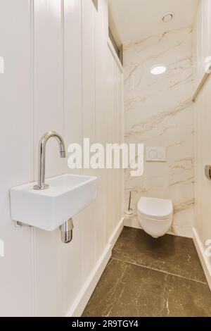 Ein weißes Bad mit Marmorboden und Wand-zu-Wand Fliesen in der Duschkabine, die auch als Toilette genutzt wird Stockfoto