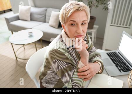 Rücksichtsvolle, reife Frau, die zu Hause arbeitet Stockfoto