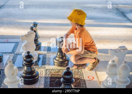 Vater und Sohn spielen Schach und verbringen Zeit zusammen im Freien. Kind spielt Schach Stockfoto