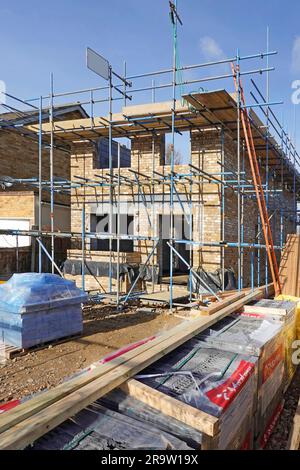 Um den neuen freistehenden Hausaufbau herum gelagerte Baumaterialien, einschließlich Dachziegeln, Holz und Dachträger, werden im Bau von Essex England UK gelagert Stockfoto