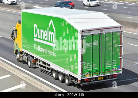 Gelber DHL-Lkw mit Lkw-Aufzug, der einen grünen Dunelm-Einzelhandelsmöbel für den Wohnungsbau schleppt, Lkw-Karosserie, Zugang über die Hintertür, knickgelenkter Auflieger, UK-Straße Stockfoto