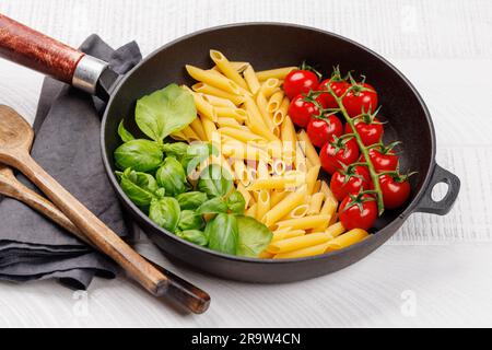 Eine lebendige Darstellung der italienischen Flagge mit Pasta, Basilikum und Tomaten, wunderschön präsentiert in einer Pfanne Stockfoto