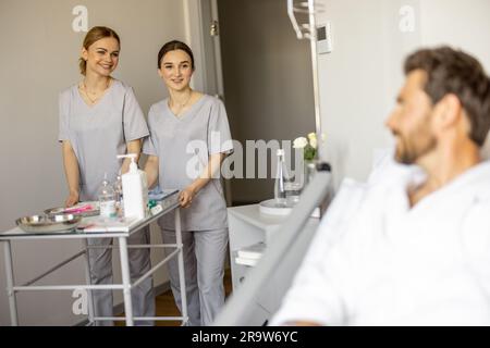 Krankenschwestern besuchen Patienten auf der Krankenstation Stockfoto