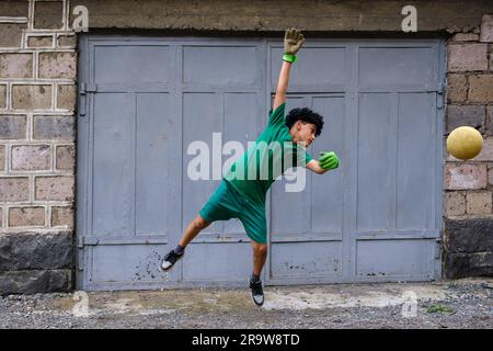 Ein Junge mit Ball als Torhüter in einem Hinterhof in Vagharshapat Stockfoto