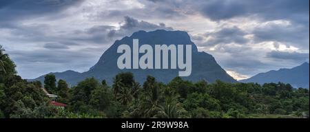 Malerisches Landschaftspanorama des mächtigen Doi Luang Chiang Dao Kalksteinbergs bei Sonnenuntergang unter bewölktem Monsunhimmel, Chiang Dao, Chiang Mai, Thailand Stockfoto