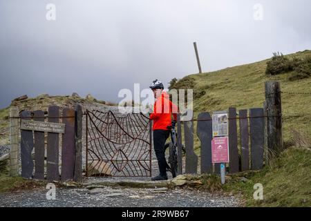 Zwei Männer fahren mit dem Mountainbike den Llanberis Path hinauf zum Gipfel des Snowdon (Yr Wyddfa) in Snowdonia, Wales im Februar. Stockfoto