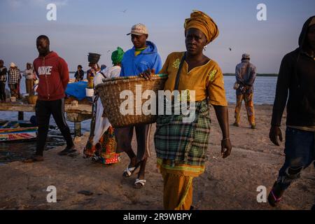 Die Marktfrau läuft mit einem Korb auf einem Fischmarkt in Dakar, Senegal Stockfoto