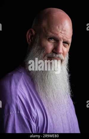 Porträt eines Mannes mit langem grauem Bart, der ein lilafarbenes T-Shirt im Nahaufnahme-Porträt trägt Stockfoto