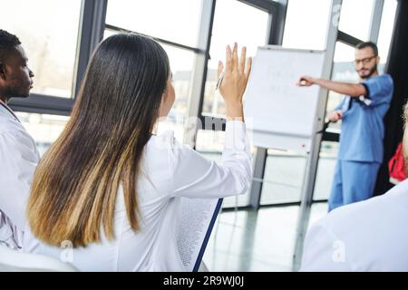 Erste-Hilfe-Seminar, verschwommene medizinische Lehrerin zeigt Kompressionsstrumpf, junge Frau fragt nach der Suche in der Nähe einer multiethnischen Gruppe, Notfall vorbereitet Stockfoto