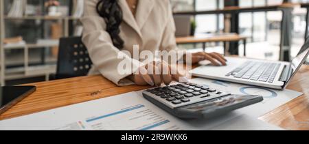 Nahaufnahme der Hände einer Geschäftsfrau mit einem Taschenrechner zur Überprüfung von Unternehmensfinanzen, -Einnahmen und -Budgets. Geschäftsfrau, die die monatlichen Ausgaben berechnet Stockfoto