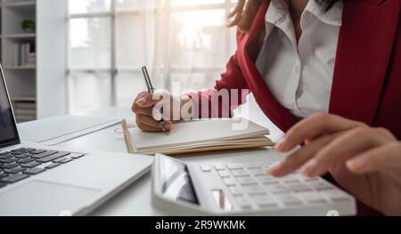 Nahaufnahme der Hände einer Geschäftsfrau mit einem Taschenrechner zur Überprüfung von Unternehmensfinanzen, -Einnahmen und -Budgets. Geschäftsfrau, die die monatlichen Ausgaben berechnet Stockfoto