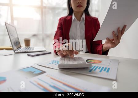 Nahaufnahme der Hände einer Geschäftsfrau mit einem Taschenrechner zur Überprüfung von Unternehmensfinanzen, -Einnahmen und -Budgets. Geschäftsfrau, die die monatlichen Ausgaben berechnet Stockfoto