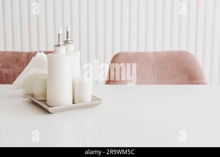 Küchenständer mit Gewürzgläsern auf weißem Holztisch. Salz, Pfeffer, Öl und Essig. Vorderansicht Stockfoto