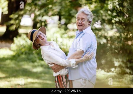 Deutschland, ein älteres Paar, das für den Sommer gekleidet ist, sich umarmt und Spaß in der Natur hat, Europa Stockfoto