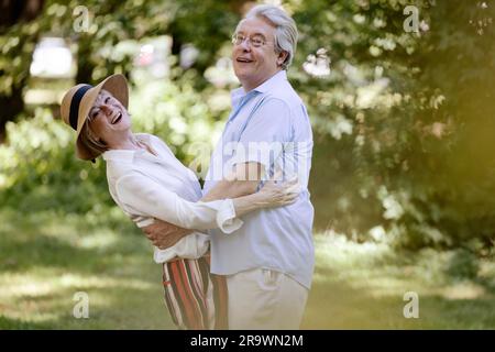 Deutschland, ein älteres Paar, das für den Sommer gekleidet ist, sich umarmt und Spaß in der Natur hat Stockfoto