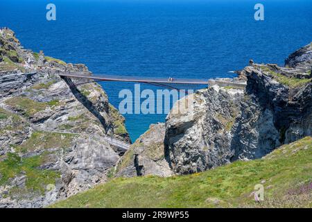 Touristen gehen über die neue Fußgängerbrücke zur Halbinsel mit den Burgruinen von Tintagel Castle, North Cornwall, England, Großbritannien Stockfoto