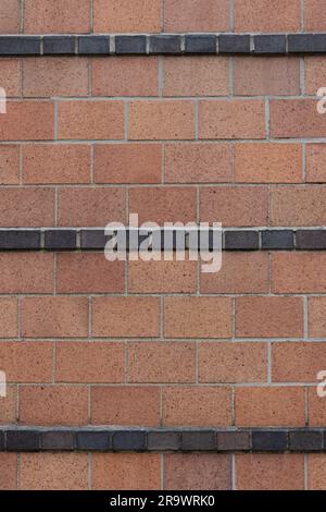 terra-Cotta-Steine in Bahre- oder fließendem Bindungsmuster mit Streifen aus schwarzen Halbsteinen schaffen ein handwerkliches dekoratives Bauwerk im Art déco-Stil Stockfoto
