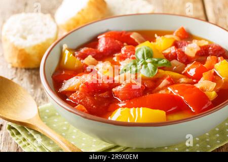 Warmer Salat aus gedünsteten bunten Paprika mit Zwiebeln und Tomaten in einer Schüssel auf dem Tisch. Horizontal Stockfoto