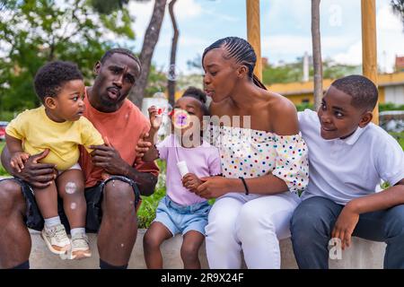 Afrikanische schwarze ethnische Familie mit Kindern auf dem Spielplatz, die Seifenblasen blasen Stockfoto