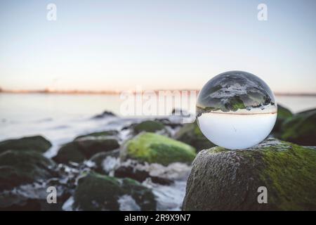 Glas Orb auf den Felsen, vom Meer bedeckt mit Moos Stockfoto