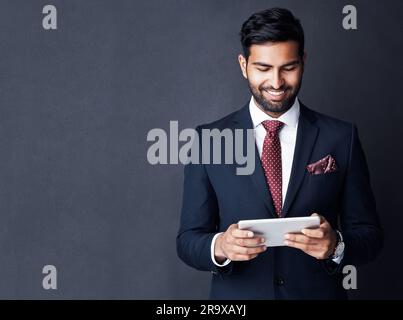Zufriedener Geschäftsmann und Tablet auf dunklem Hintergrund im Studio mit Mockup-Platz für Handel, Planung und Internetrecherche. Firmenkunden, indischer Mann Stockfoto