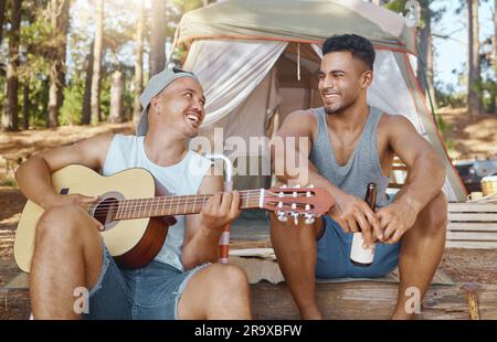 Männer, Freunde und Gitarre zum Campen im Wald mit Lächeln, Gesang und Bier für Getränke, Entspannung und Urlaub. Junge männliche Studenten, Musiker und glückliche Menschen Stockfoto